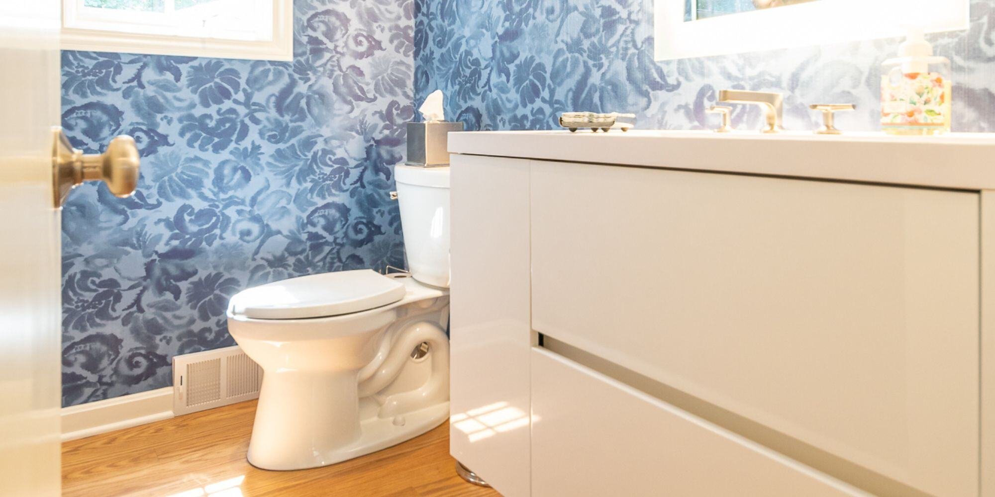 blue wallpapered half bathroom with floating white vanity